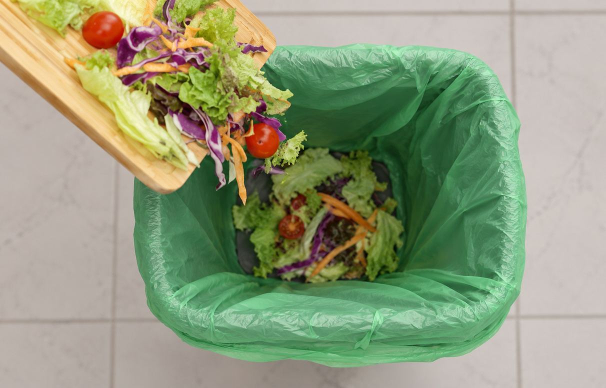 Salad scraps tipped into a lined compost bin